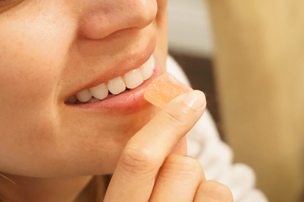 Bottom half of a woman’s face eating a CBD gummy